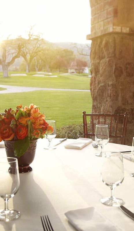 Table set for an intimate outdoor dinner overlooking a golf course at golden hour
